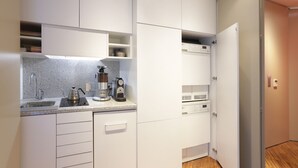 Ett modernt kök med vita skåp, en bänkskiva i granit, en kaffebryggare och en vattenkokare.