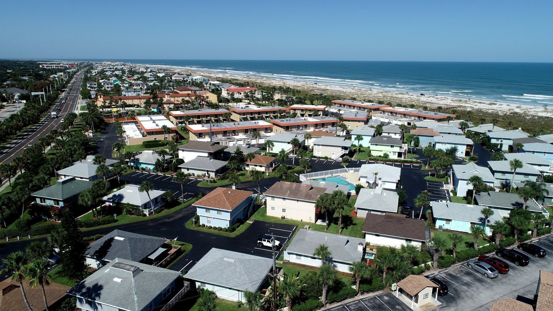 A coastal residential area with houses, a beach, and a clear view of the ocean.