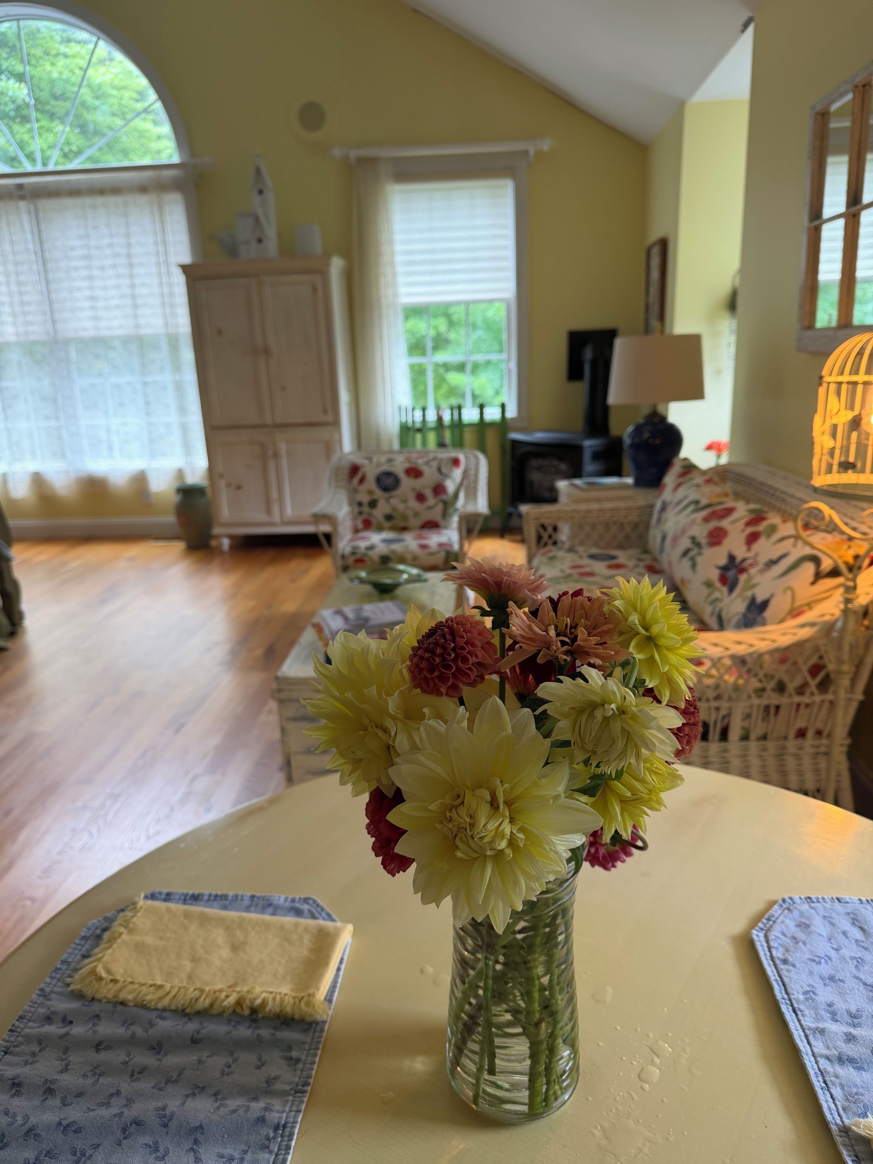 A room with a floral arrangement on a table, a sofa, and a cabinet.