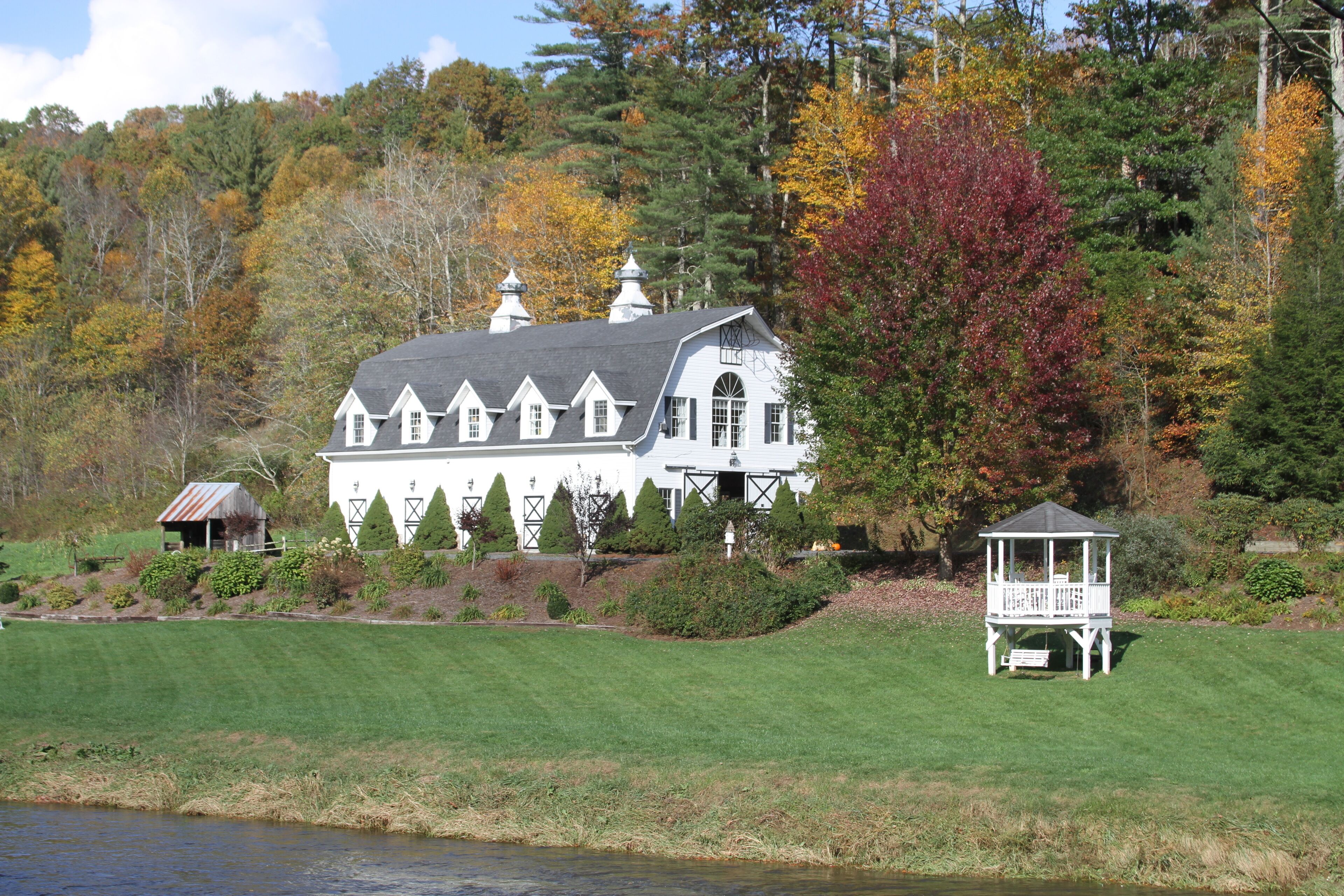 A large white house with multiple chimneys and a gazebo in a lush, green landscape.