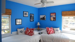 Una habitación con dos camas, paredes azules y cuadros enmarcados.