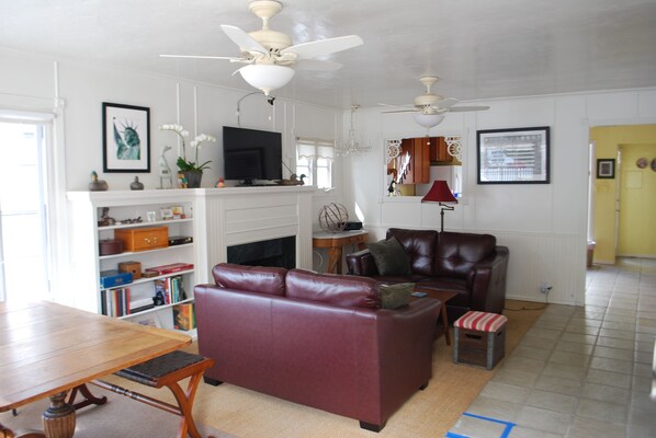 A living room with a fireplace, leather sofa, wooden coffee table, and ceiling fans.