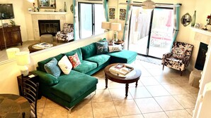 Un salon avec un canapé vert, une table basse ronde, une cheminée et un téléviseur.