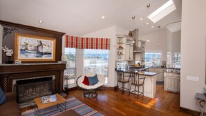 A spacious living room with a fireplace, a dining area with bar stools, and a kitchen with white cabinetry. - Laguna Beach Tranquility Base across from Jr. High.  Long Term Discounts (Laguna Beach)