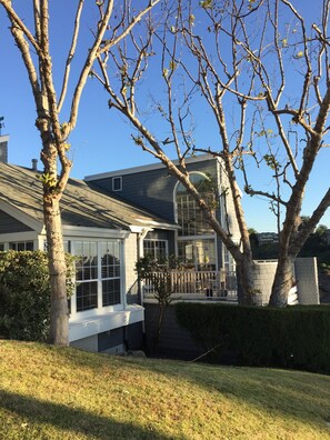 A residential house with a large window, a covered porch, and a well-maintained lawn.