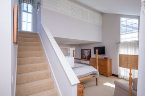 A bedroom with a loft bed, a dresser, a TV, and a lamp.