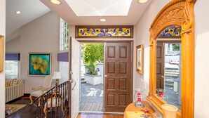 A well-lit hallway with a wooden floor, a staircase, a door leading outside, and a large mirror with a decorative frame. - Laguna Beach Tranquility Base across from Jr. High.  Long Term Discounts (Laguna Beach)