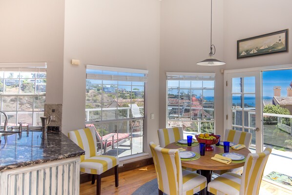A dining area with a large window, a kitchen counter, and striped chairs.