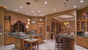 A spacious kitchen with wooden cabinetry, a central island with seating, and pendant lighting.