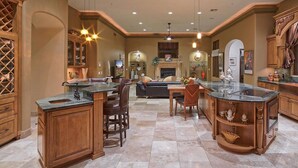 A spacious kitchen with a central island, wooden cabinetry, and a dining area with a sofa.