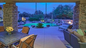 A patio area with a pool, stone walls, outdoor furniture, and a view of the surrounding landscape.