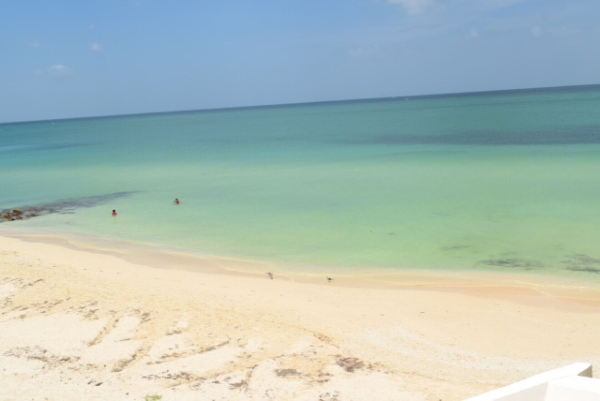 A beach with clear turquoise water and a sandy shore.