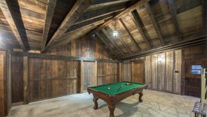 Ein Billardtisch in einem Raum mit Holzwänden und Steinboden.