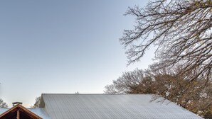 Ein rustikales Gebäude im Stil eines Bauernhauses mit Metalldach, Holzfassade und überdachter Veranda.