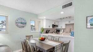 Una cocina moderna con armarios blancos, un microondas y un comedor con mesa y sillas.