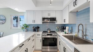Una cocina moderna con armarios blancos, electrodomésticos de acero inoxidable y un salpicadero de azulejos azules.