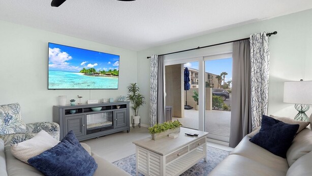 Una sala de estar con televisor, sofá, mesa de centro y vistas al exterior.