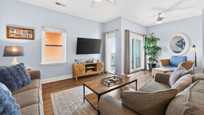 Una sala de estar con televisor, sofá, mesa de centro y planta.
