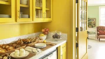 A kitchen with yellow cabinets, a stainless steel dishwasher, and a breakfast bar with various food items.