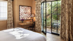 A bedroom with a bed, a desk, a chair, a lamp, and a large window with curtains. - Hotel 850 SVB, a Member of Design Hotels (West Hollywood)