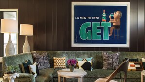 A modern living room with a green sofa, patterned cushions, a wooden coffee table, and a framed poster on the wall. - Hotel 850 SVB, a Member of Design Hotels (West Hollywood)