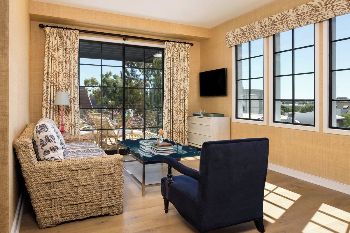 A living room with a sofa, armchair, and a table with books and a vase.