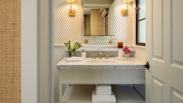 A bathroom with a marble sink, two wall-mounted lamps, a mirror, and a window. - Hotel 850 SVB, a Member of Design Hotels (West Hollywood)