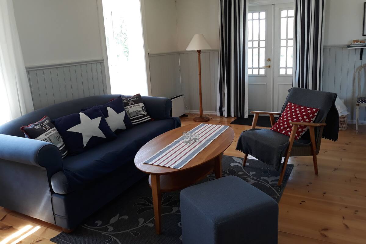 A living room with a dark blue sofa, a wooden coffee table, and a grey armchair.