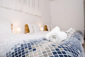 Une chambre d’hôtel avec un lit bien fait, une lampe de chevet et une fenêtre ornée de rideaux légers.