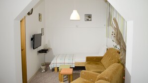 A small, cozy room with a single sofa, a small table, and a TV mounted on the wall. - Villa Re3Ca (Skopje)