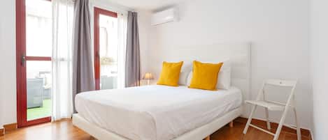 Un dormitorio con cama, una silla y vistas a un espacio exterior.