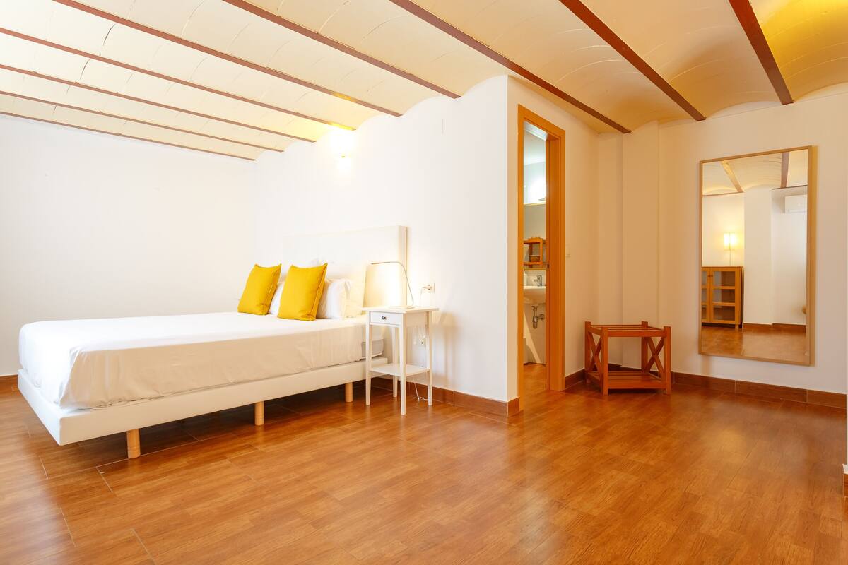 Un dormitorio con cama, mesita de noche y espejo en la pared.
