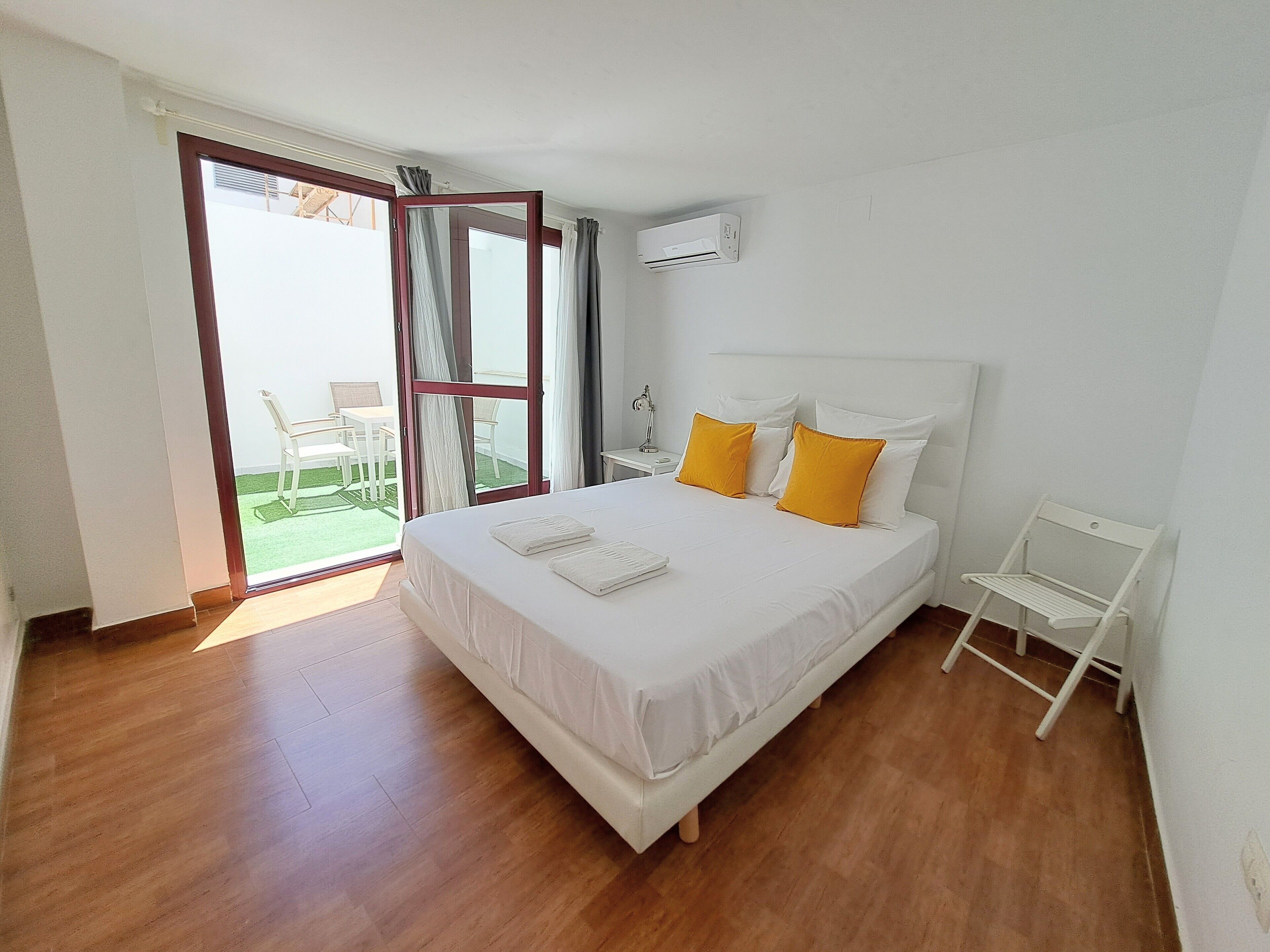 Quarto com cama grande, mesa de cabeceira, ar condicionado e vista para o exterior.