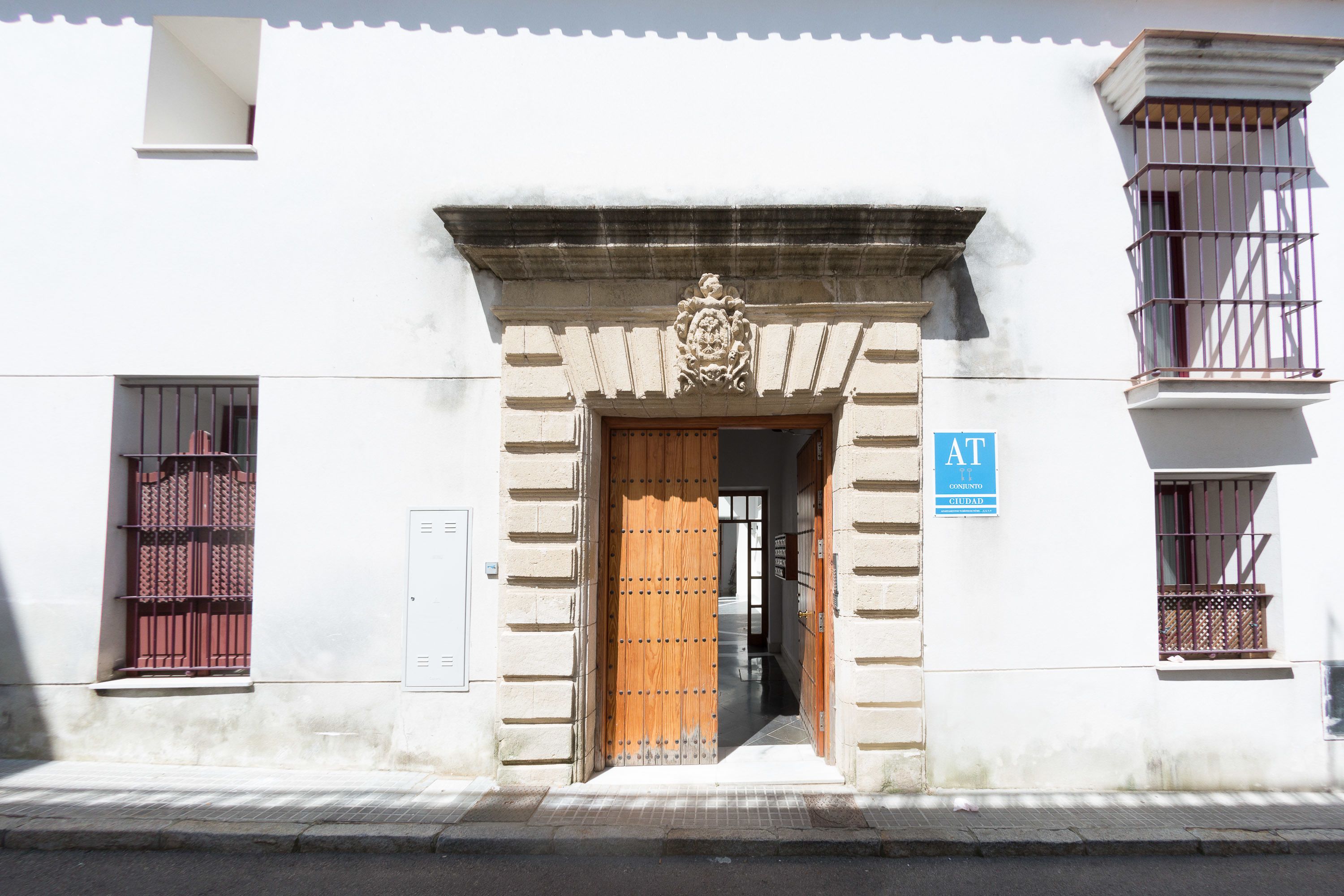 A building entrance with a wooden door, a stone facade, and a sign indicating it is a public building.