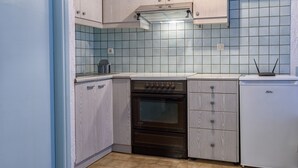 Una cocina con armarios de madera clara, un horno negro y un lavavajillas blanco.