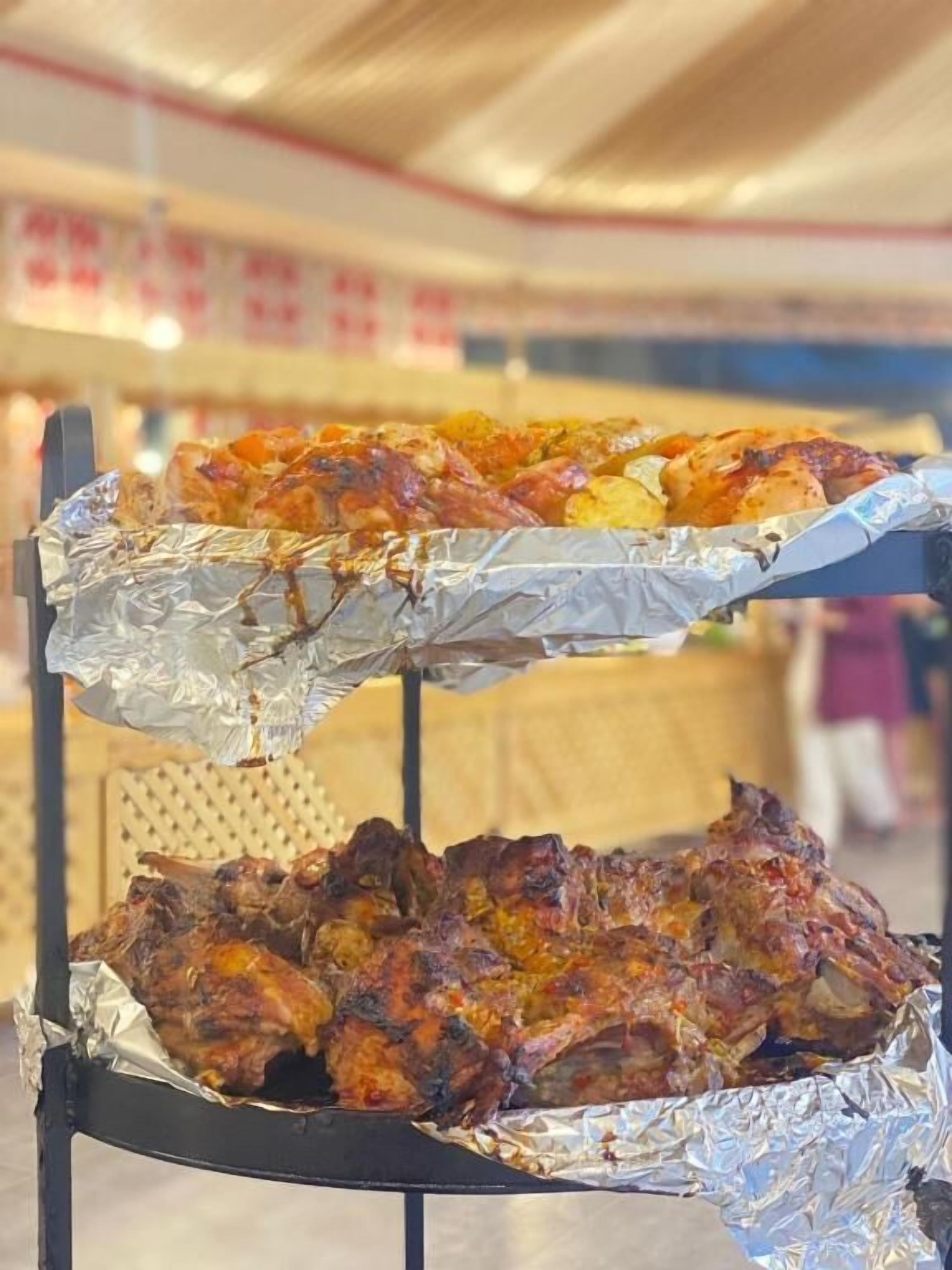 Un barbecue avec différentes sortes de viandes et de légumes, probablement lors d’un événement en plein air ou dans un marché.