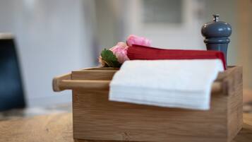 A wooden chest with a white cloth and a red cloth on top, a pink flower, and a pepper grinder.