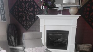 Un salón acogedor con chimenea, dos gatos esponjosos y almohadones decorativos.