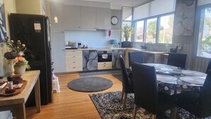 Una cocina moderna con horno empotrado, refrigerador y comedor con mesa y sillas.
