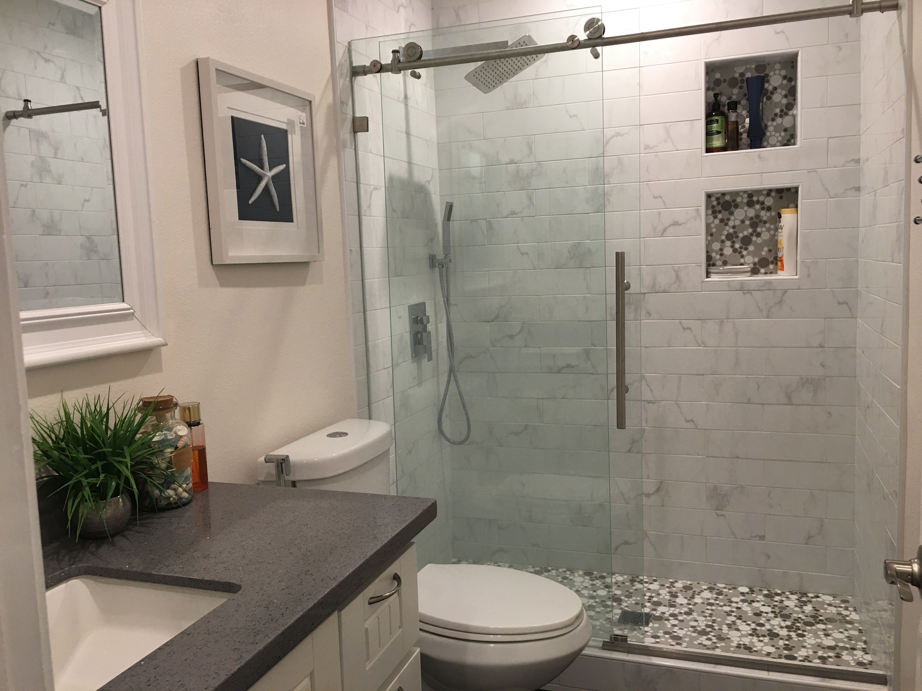 Een moderne badkamer met een glazen douchecabine, een toilet en een wastafel.