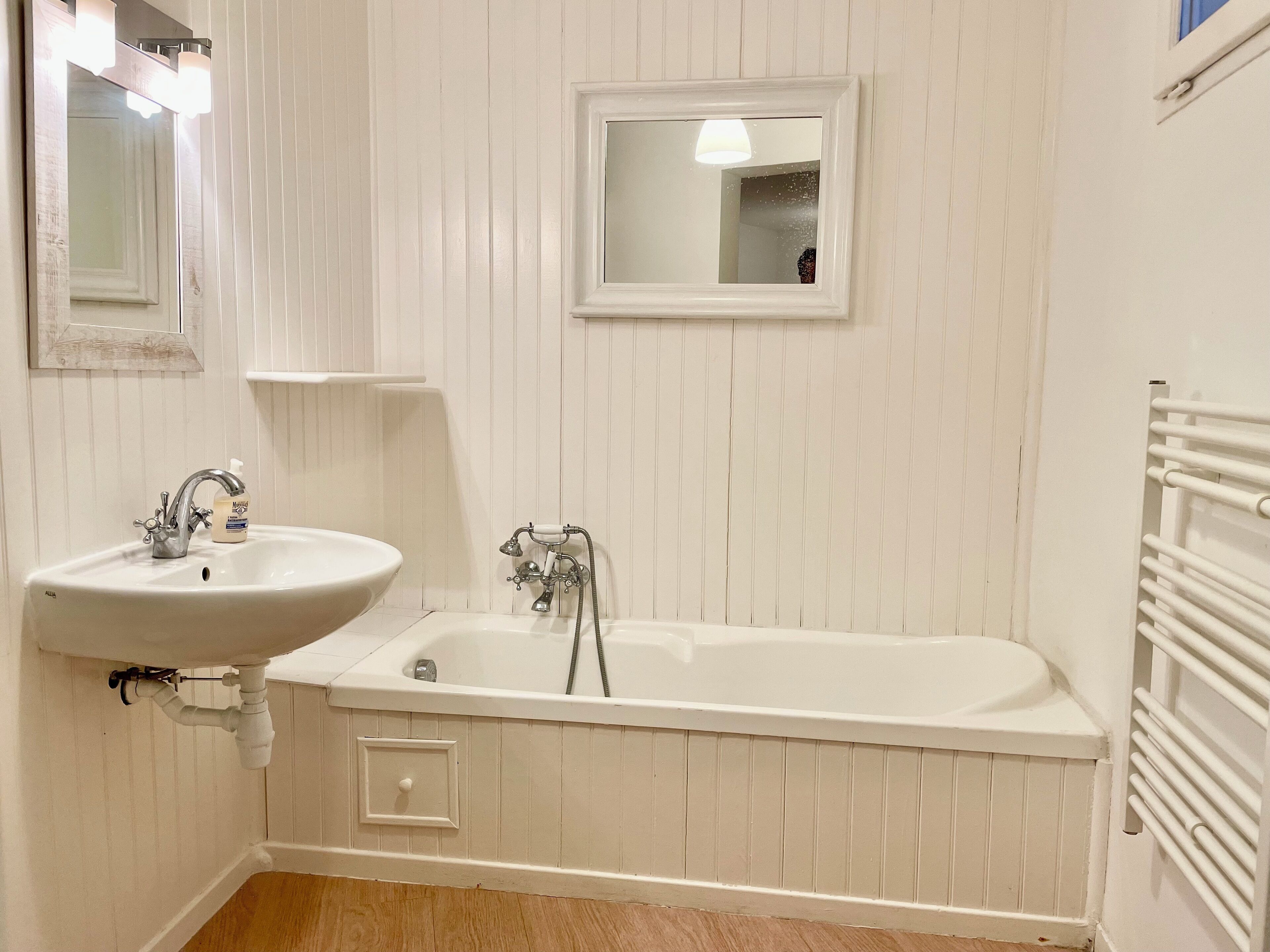 Ein Badezimmer mit einem weißen Waschbecken, einem Spiegel und einer Badewanne.