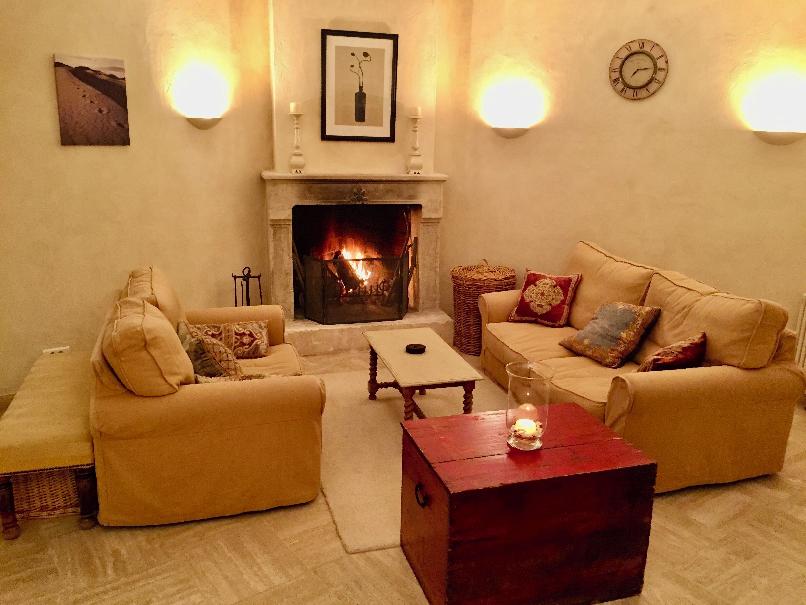 Ein gemütliches Wohnzimmer mit Kamin, zwei Sofas, einem Couchtisch und einem Beistelltisch mit Kerze.