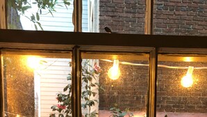 A window with multiple panes, each displaying a view of a garden with string lights and plants. - Duvall House - George Washington ate here! In the heart of Old Town Alexandria.  (Alexandria)