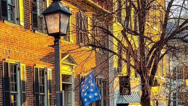 A brick building with a flag, a lamp post, and a statue. - Duvall House - George Washington ate here! In the heart of Old Town Alexandria.  (Alexandria)