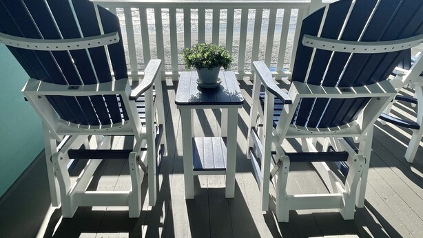 Une terrasse avec deux chaises Adirondack et une petite table sur laquelle est posée une plante en pot.
