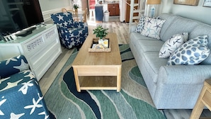 Un salon avec un téléviseur, un canapé, une table basse et des coussins à motifs.