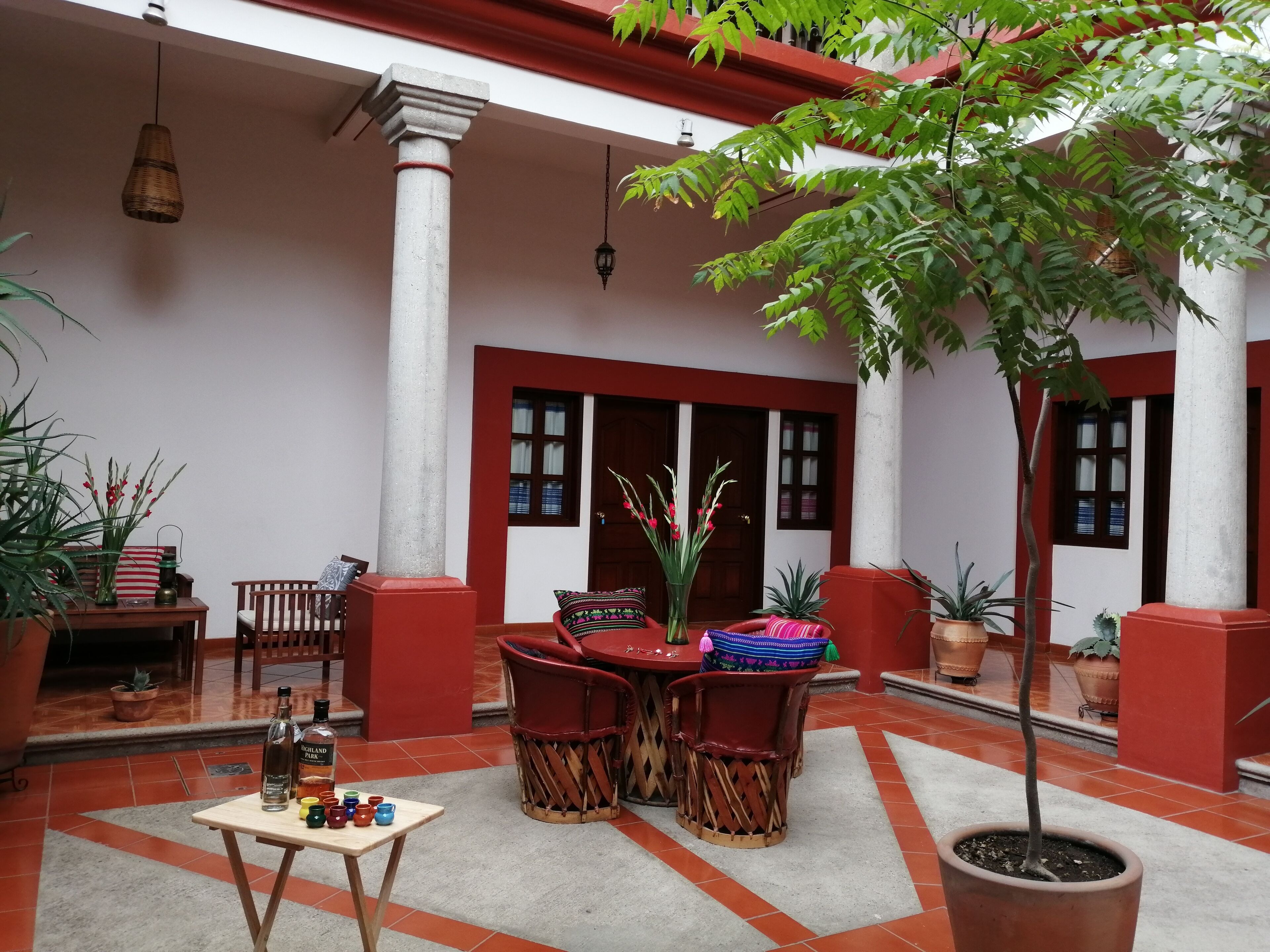 A courtyard with a table and chairs, potted plants, and a tiled floor.