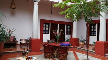 A courtyard with a table and chairs, potted plants, and a tiled floor.