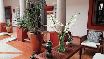 A wooden table with potted plants and a lantern in a well-lit indoor space with tiled flooring and a red and white color scheme.