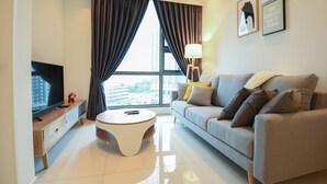 A modern living room with a sofa, a coffee table, a TV, and a large window with curtains.